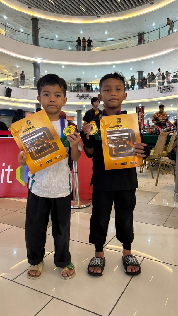 Dua pelajar muda GTP memegang pingat emas dan sijil pencapaian